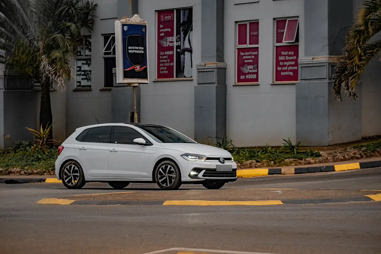 Hatch branco estacionado numa rua em frente a um prédio comercial.