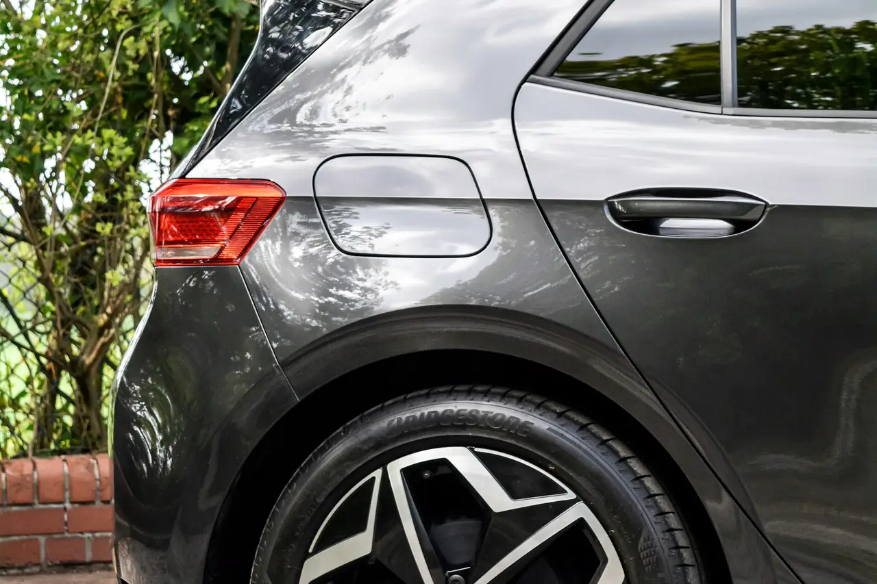 Lateral traseira de um hatch cinza estacionado.