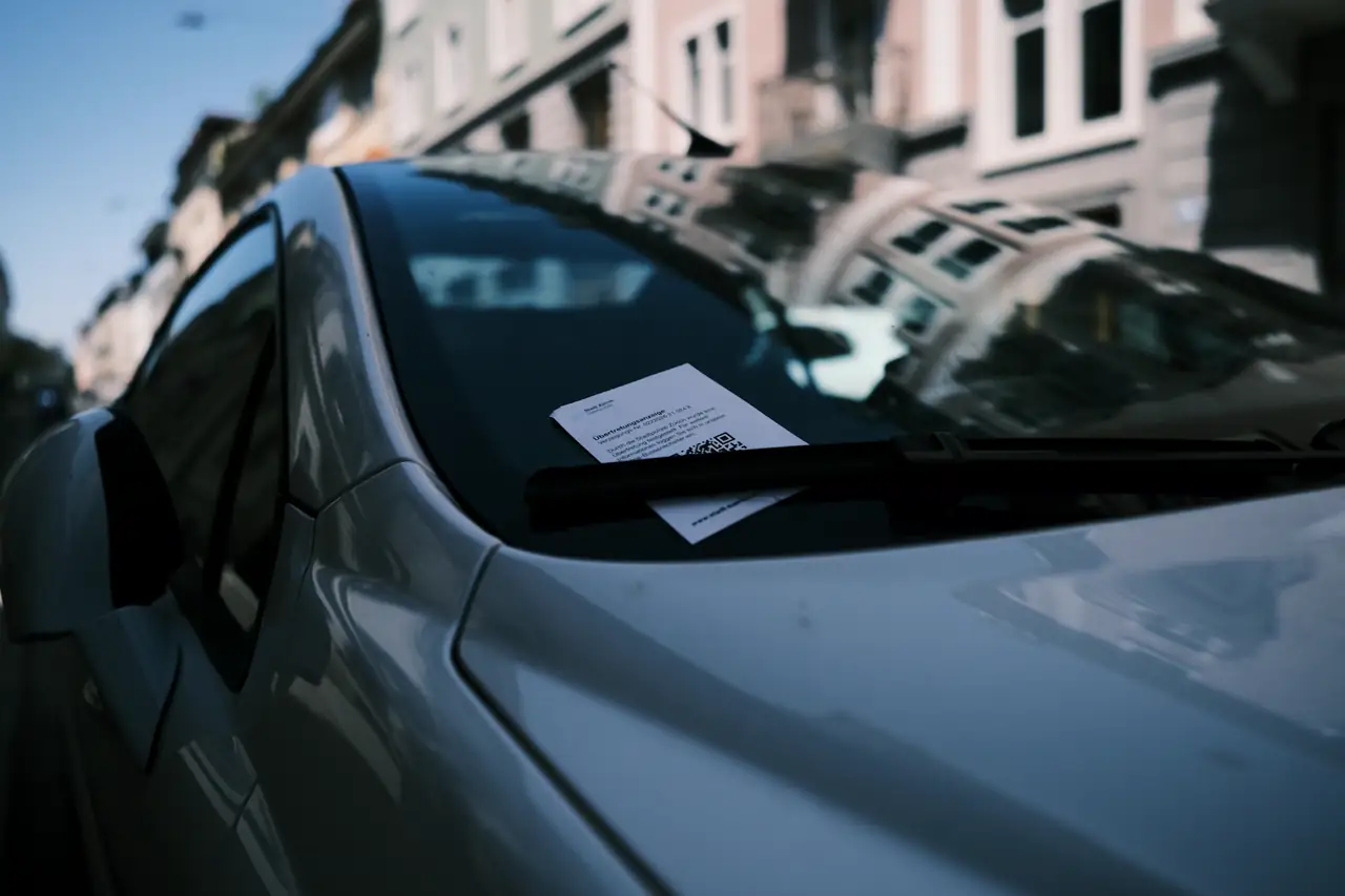 Notificação presa no limpador do para-brisa de um carro estacionado.