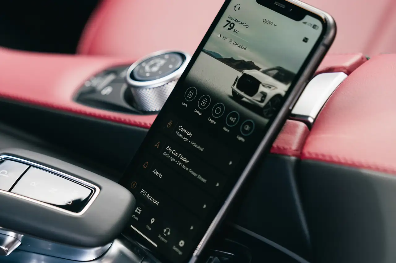 Celular apoiado no console de um carro mostrando um aplicativo do veículo.