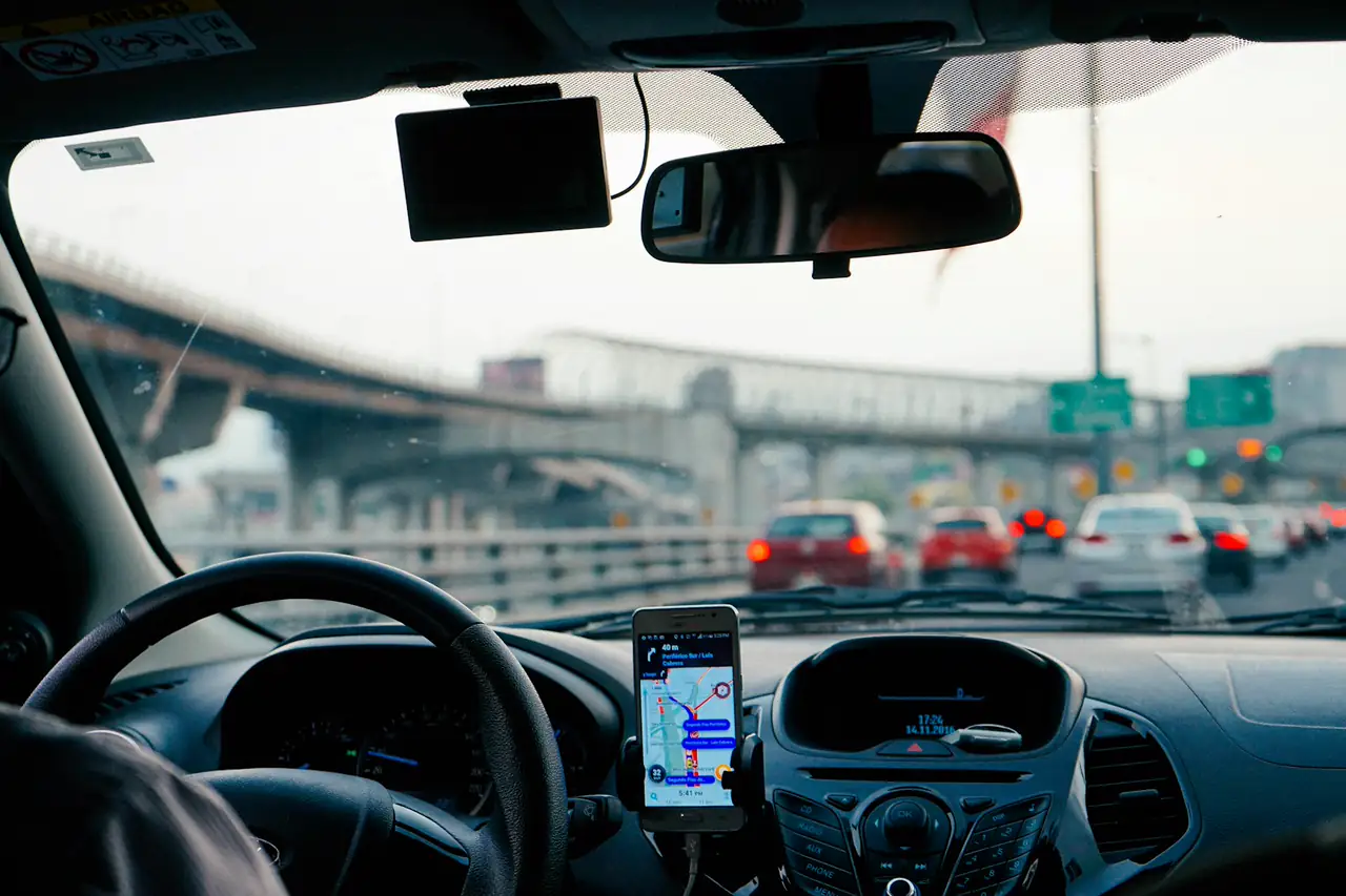 Celular com mapa preso ao painel de um carro parado no trânsito.