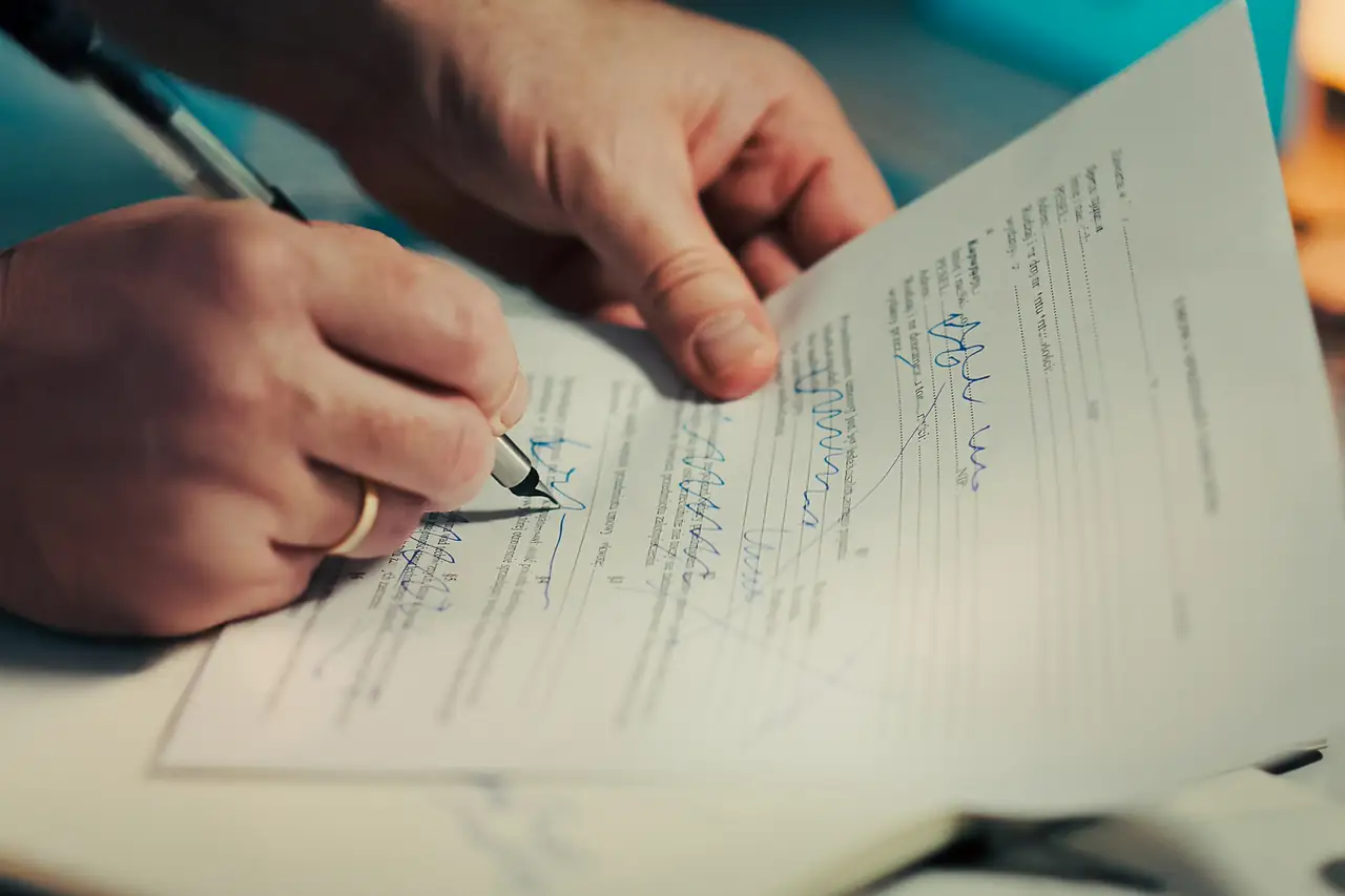 Mãos assinando um documento impresso com uma caneta.