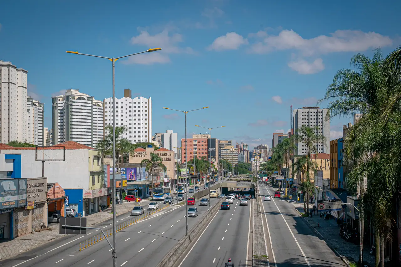 Avenida larga de uma cidade brasileira com prédios e palmeiras.