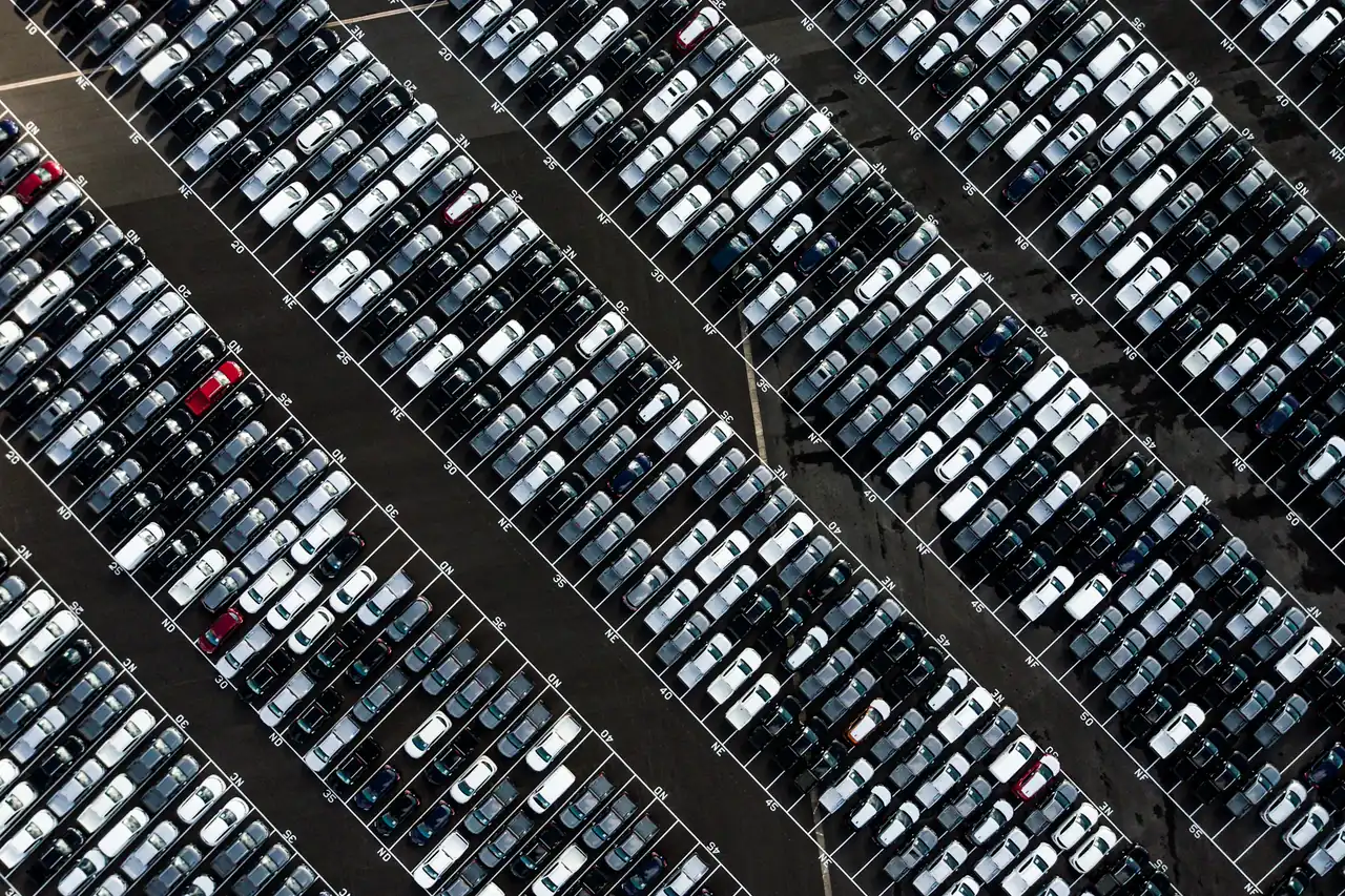 Vista aérea de um pátio enorme com centenas de carros estacionados em diagonal.