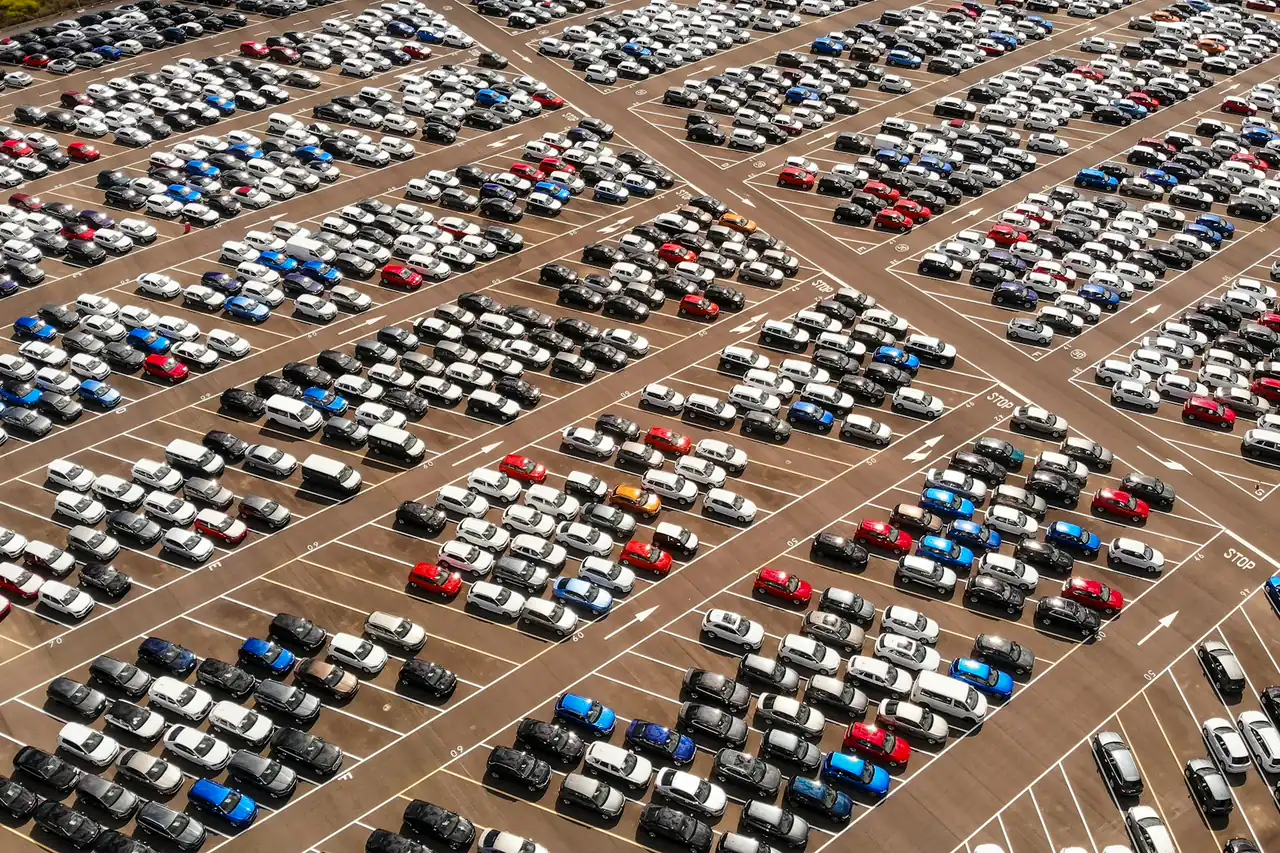 Vista aérea de um grande pátio de veículos com corredores entre as fileiras.