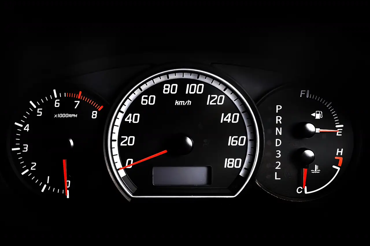 Painel de instrumentos de um carro iluminado sobre fundo escuro.