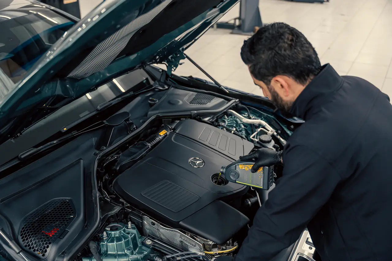 Mecânico inspecionando o motor de um carro com o capô aberto numa oficina.