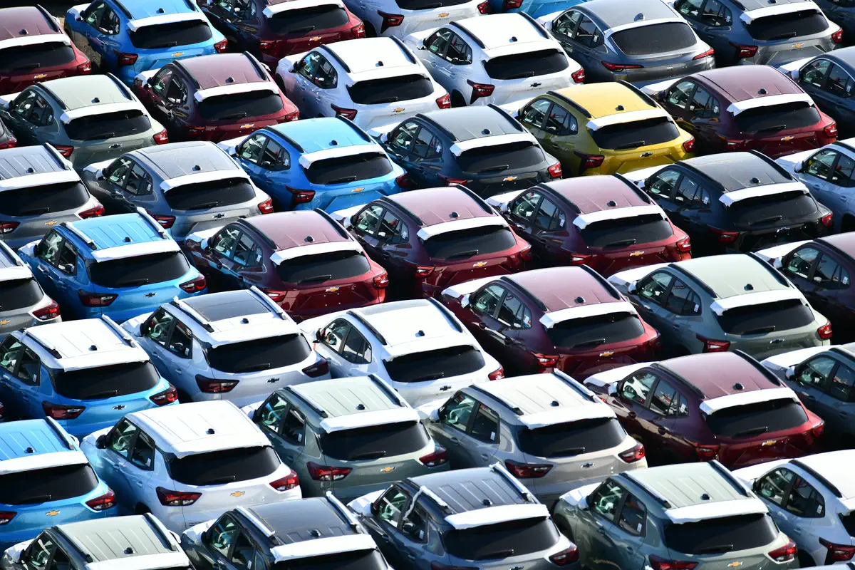 Pátio visto de cima, com fileiras de carros de várias cores estacionados lado a lado.